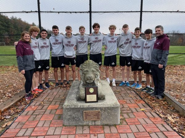 Cross Country runners and coaches pose in front of the LHS lion.